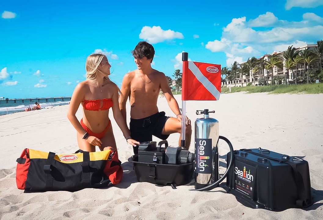Couple setting up Brownie's Sea LiON diving equipment on a beach
