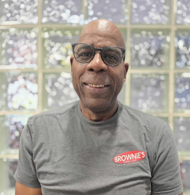 Herb, Technician at Brownie's THIRD LUNG, smiling in a gray Brownie's branded shirt