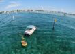 Boat supporting divers using a Brownie’s Third Lung floating dive system with yellow flotation unit and air hoses in clear tropical water near a channel marker.