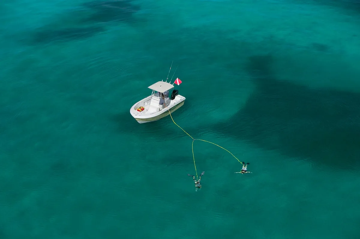 A drone view of two divers using a Brownie&rsquo;s Third Lung system beside a boat