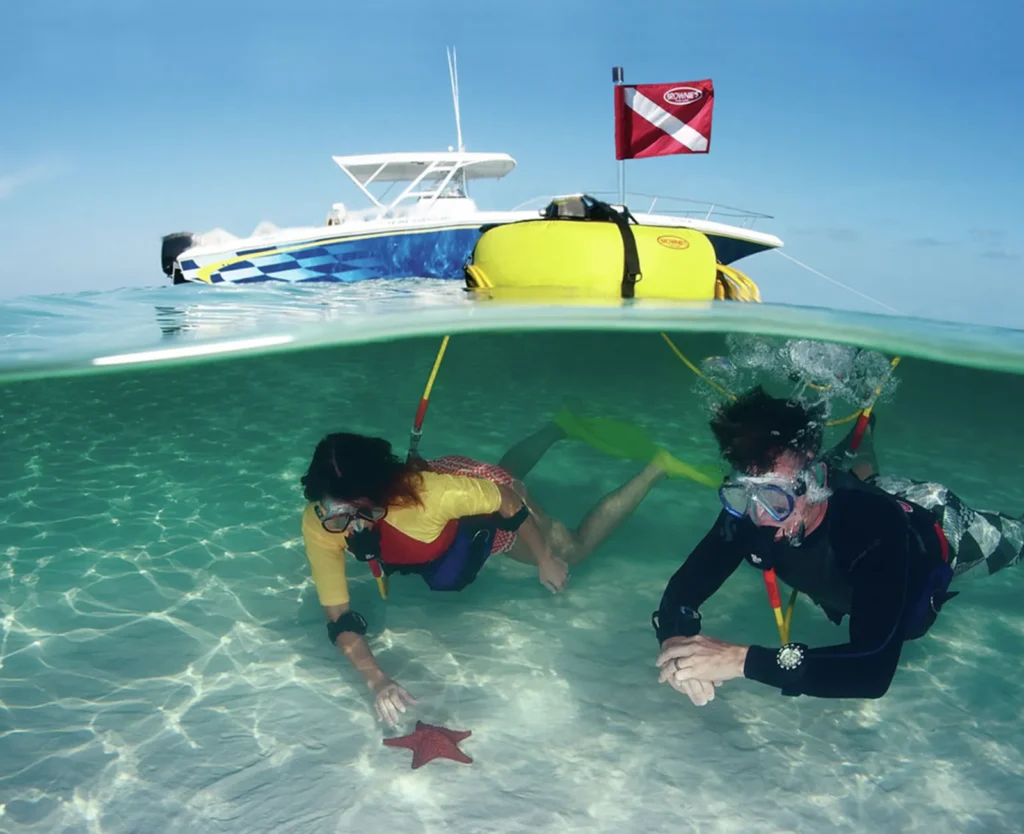 Divers using a Brownie’s Third Lung floating dive system with boat overhead in clear tropical water.