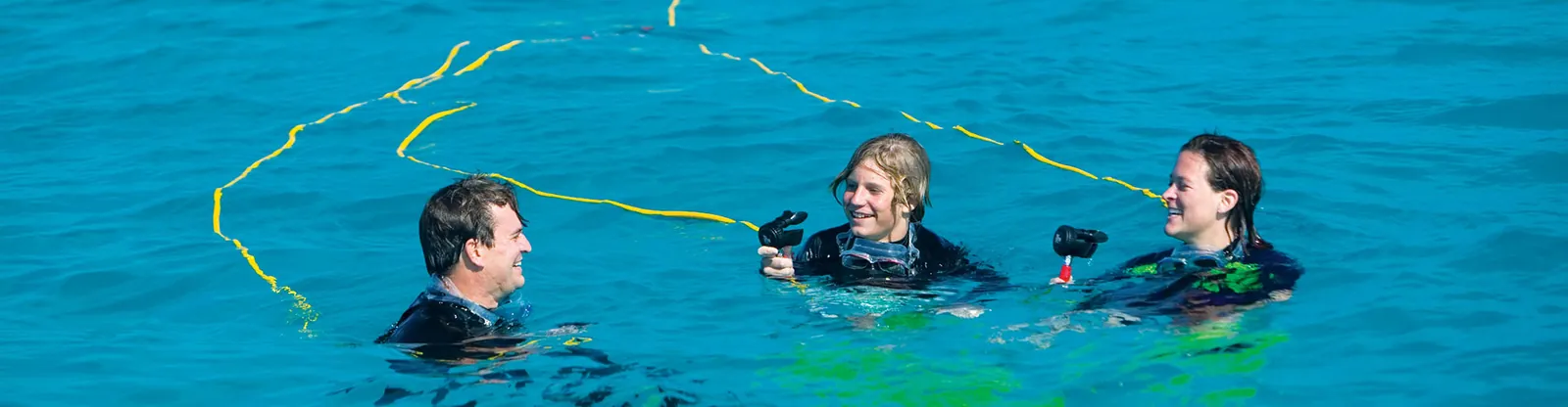 Divers at the surface breathing from a Brownie&rsquo;s Third Lung system with hoses trailing behind