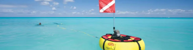 Tankless dive system floating on the water with two divers swimming in the background