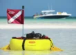Brownie's gas powered tankless dive system floating on a sandbar with a boat in the background